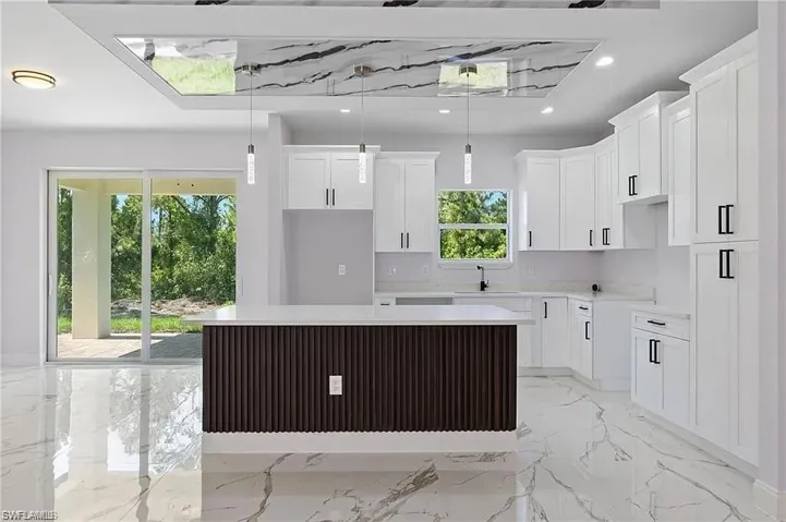 Kitchen with a center island, marble finish floor, a sink, and a healthy amount of sunlight