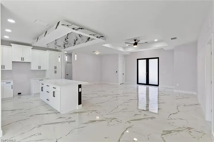 Kitchen with a center island, a tray ceiling, open floor plan, visible vents, and recessed lighting