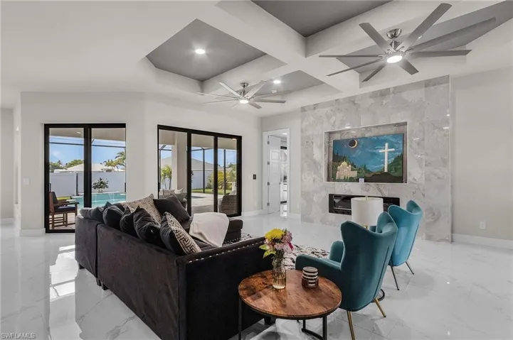 Living room featuring beamed ceiling, ceiling fan, a high end fireplace, and coffered ceiling