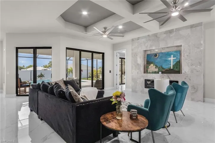 Living room with ceiling fan, a fireplace, beamed ceiling, and coffered ceiling