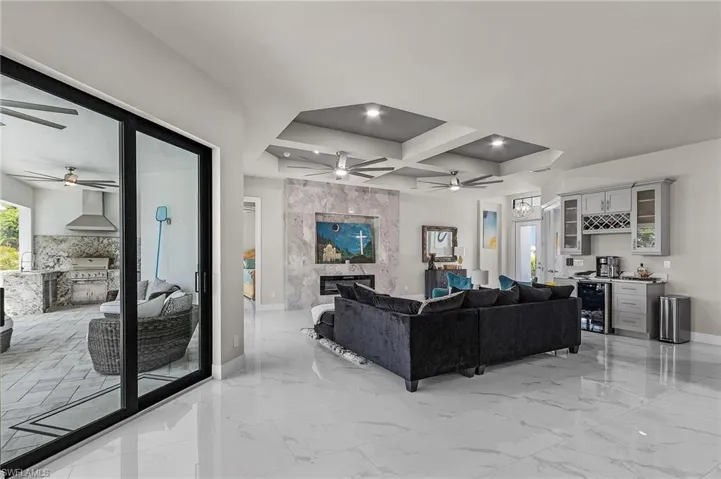 Living room featuring coffered ceiling, wine cooler, indoor bar, a premium fireplace, and beam ceiling
