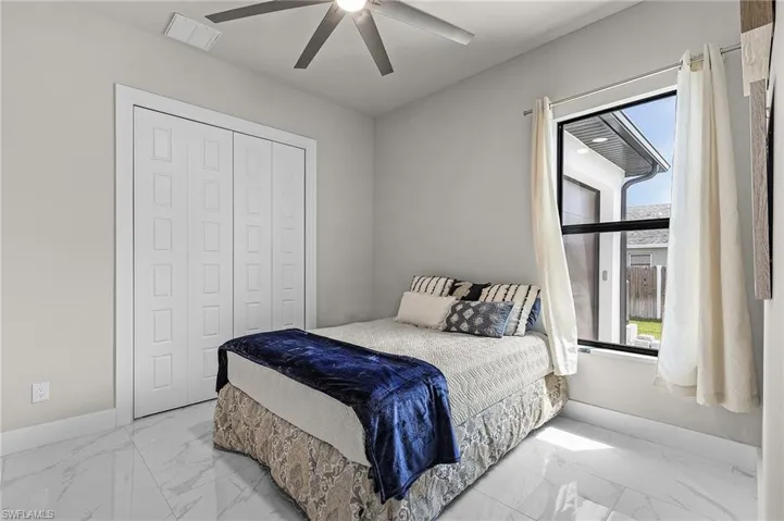 Bedroom featuring multiple windows, ceiling fan, and a closet