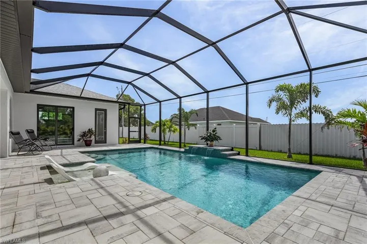 View of swimming pool featuring pool water feature, glass enclosure, and a patio area