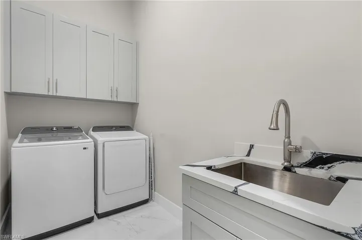 Washroom with cabinets, independent washer and dryer, and sink