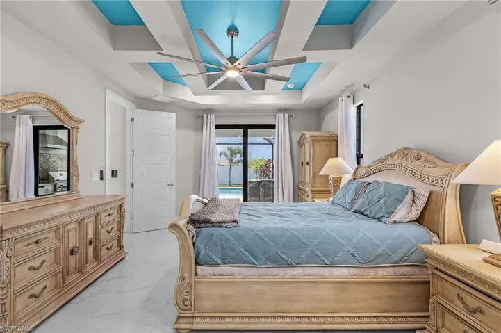 Bedroom featuring access to outside, a raised ceiling, and ceiling fan
