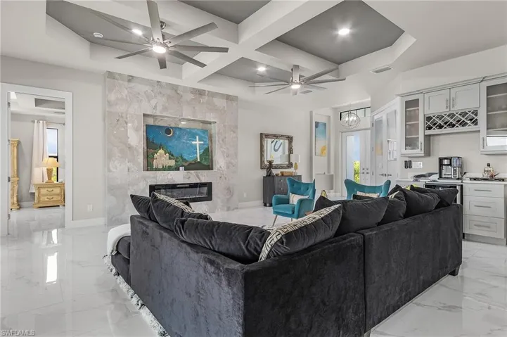 Living room with a fireplace, beamed ceiling, a chandelier, and coffered ceiling
