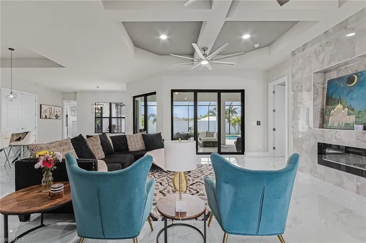 Living room featuring ceiling fan, coffered ceiling, and a tiled fireplace