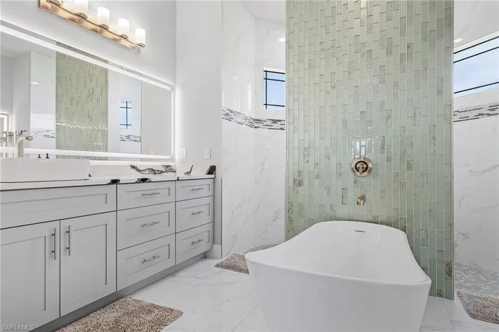 Bathroom with vanity, a healthy amount of sunlight, and plus walk in shower