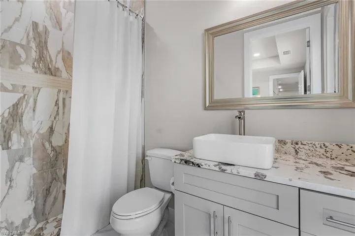 Bathroom with a shower with shower curtain, vanity, and toilet