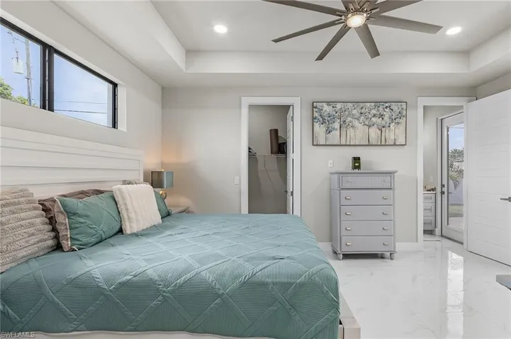 Bedroom with ceiling fan, a spacious closet, access to outside, multiple windows, and a closet