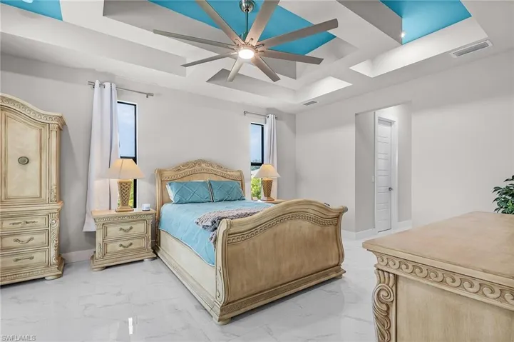 Bedroom with a raised ceiling and ceiling fan