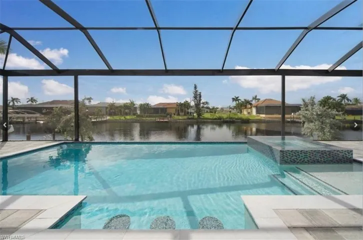 View of swimming pool featuring glass enclosure, a patio, and a water view