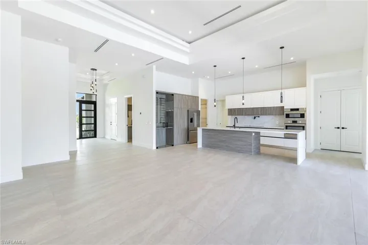 Kitchen with pendant lighting, tasteful backsplash, an island with sink, stainless steel appliances, and white cabinetry