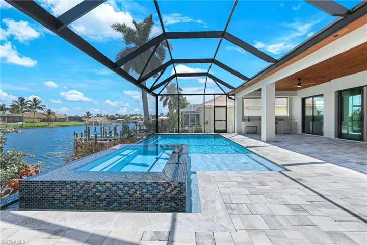 View of pool with a water view, ceiling fan, a lanai, and a patio