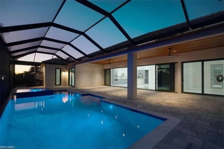 Pool at dusk featuring ceiling fan, a patio, and a lanai