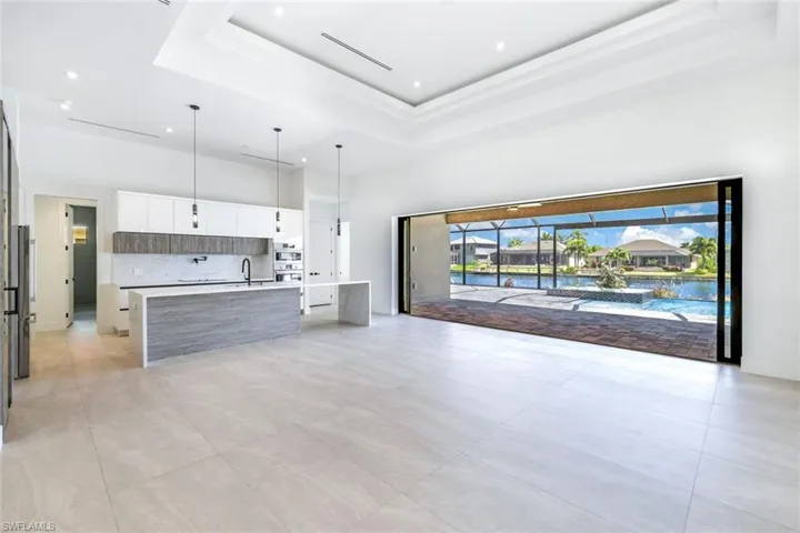 Unfurnished living room featuring a tray ceiling, sink, and a towering ceiling
