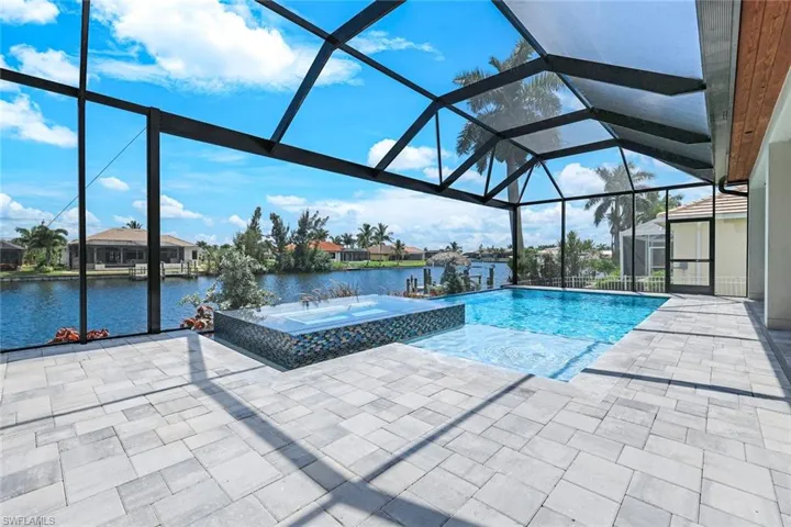 View of pool featuring a water view, a patio, and glass enclosure