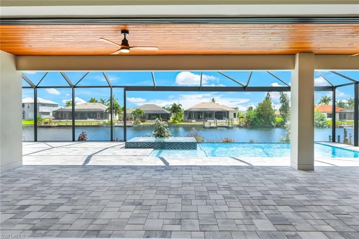 View of pool featuring a water view, ceiling fan, a lanai, and a patio area