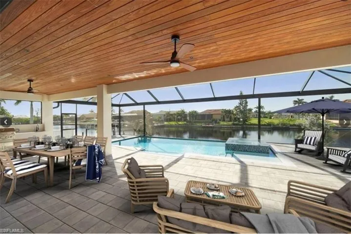 View of swimming pool featuring a water view, a lanai, ceiling fan, and a patio area