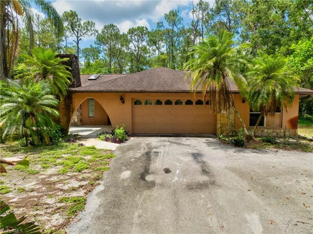 View of front facade with a garage, stucco siding, driveway, and stone siding