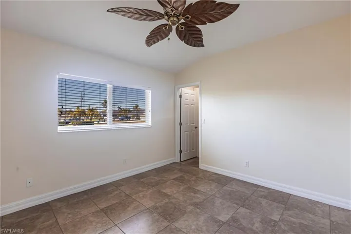 Unfurnished room featuring baseboards, a ceiling fan, and lofted ceiling