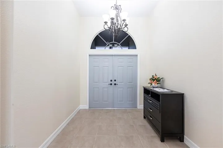 Foyer featuring light tile patterned floors, baseboards, and a notable chandelier