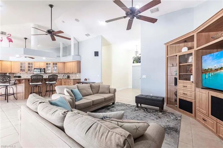 Living area featuring light tile patterned floors, visible vents, high vaulted ceiling, and a ceiling fan