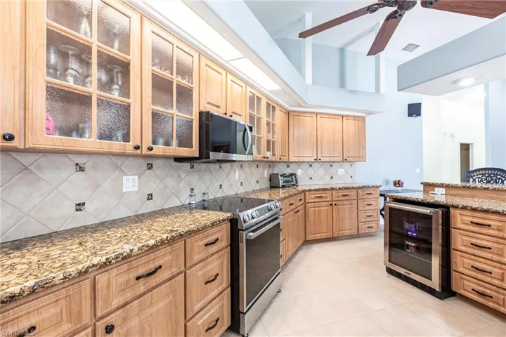 Kitchen with wine cooler, visible vents, stainless steel appliances, and light stone counters