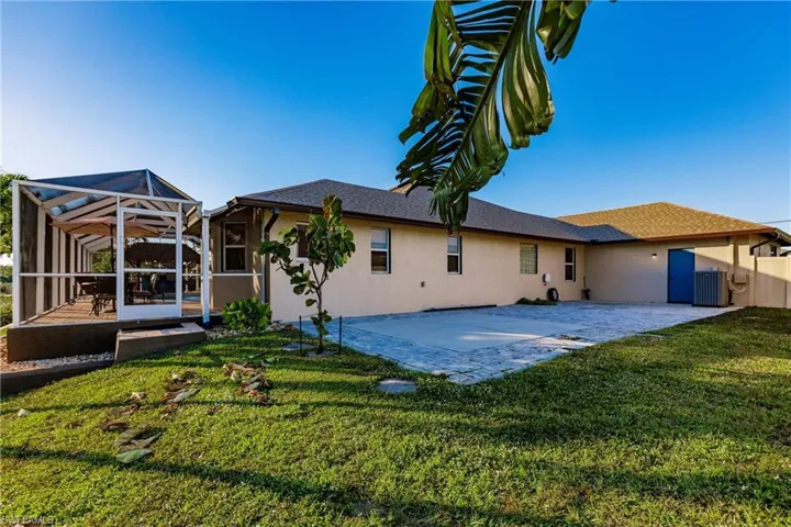 Back of property with glass enclosure, a patio area, a yard, and central AC
