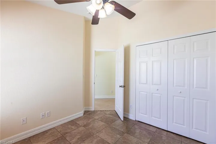 Unfurnished bedroom featuring a closet, tile patterned flooring, a ceiling fan, and baseboards