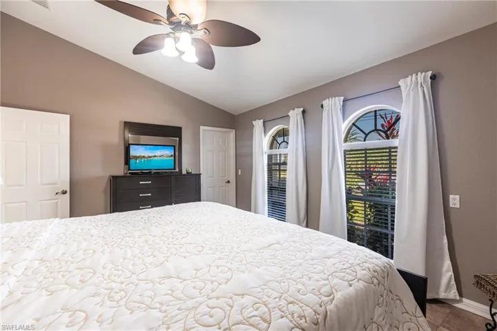 Bedroom with vaulted ceiling, baseboards, and ceiling fan