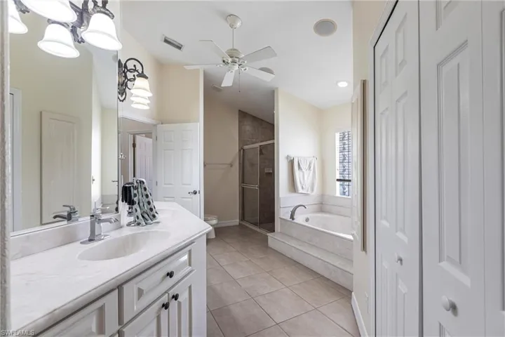Bathroom featuring tile patterned flooring, toilet, a garden tub, a stall shower, and vanity