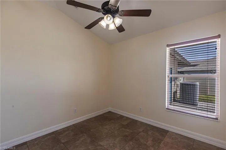Empty room with baseboards, lofted ceiling, and a ceiling fan