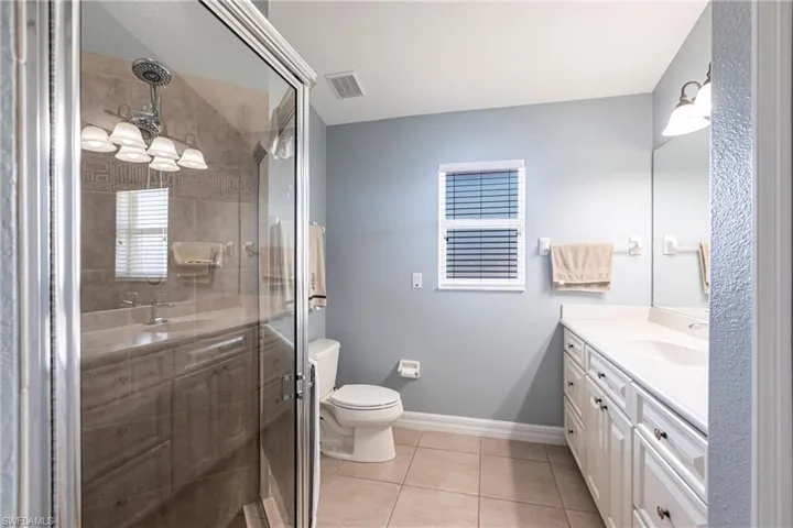 Full bath featuring tile patterned flooring, visible vents, baseboards, a stall shower, and vanity