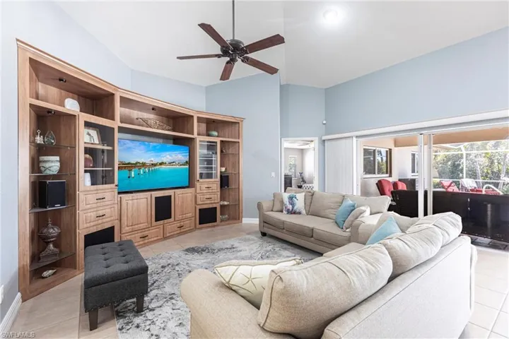 Living area with light tile patterned floors, baseboards, and ceiling fan