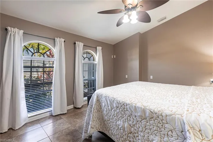 Tiled bedroom featuring visible vents, baseboards, and a ceiling fan