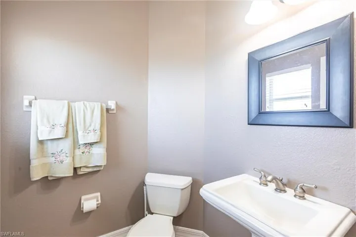 Half bath with toilet, a textured wall, and a sink
