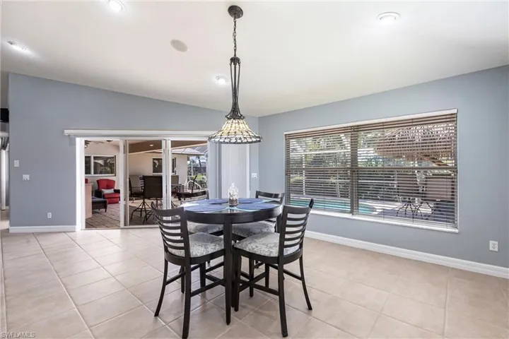 Dining area with light tile patterned floors, baseboards, and lofted ceiling