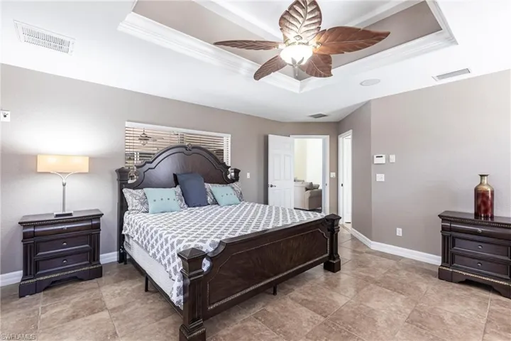 Bedroom with visible vents, a raised ceiling, baseboards, and ornamental molding