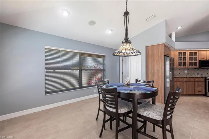 Dining area with vaulted ceiling, recessed lighting, visible vents, and baseboards