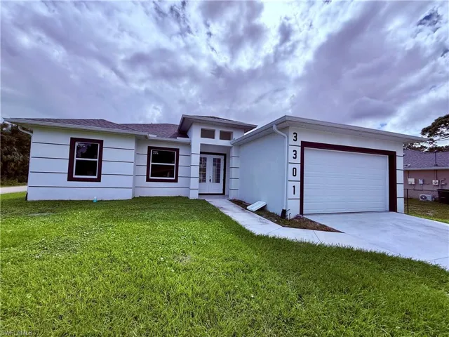 Single-story exterior featuring white stucco finish with decorative horizontal banding, dark-trimmed windows, a double-entry door with glass panels, and an attached garage