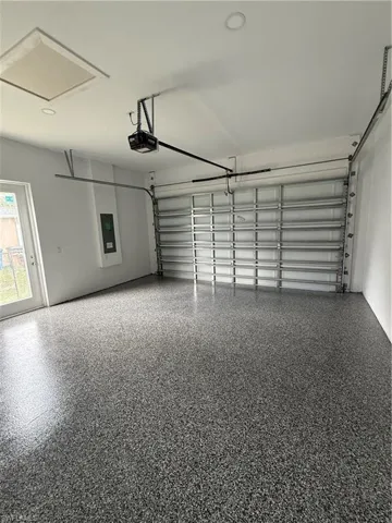 Finished garage featuring speckled epoxy flooring, recessed lighting, and a glass-paneled pedestrian door