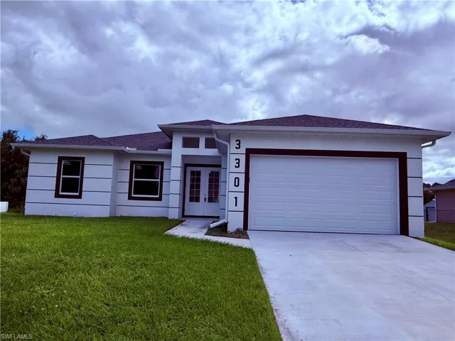 Single-story exterior featuring a light-colored stucco facade, horizontal accent banding, a double-door entryway with transom window, and an attached two-car garage