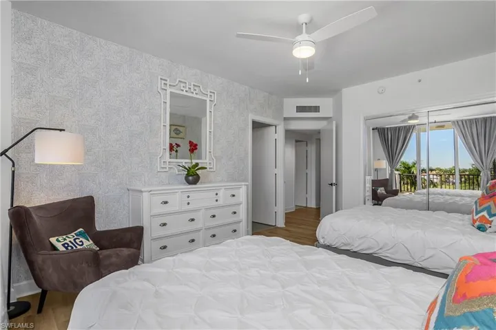 Guest Bedroom a large guest closet, en suite full bath with light wood-style flooring, access to exterior, a ceiling fan, and wallpapered walls