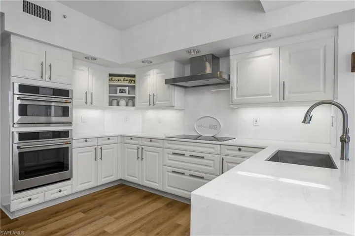 Kitchen with white cabinetry,quartz countertop and backsplash, open shelves, and stainless steel double oven