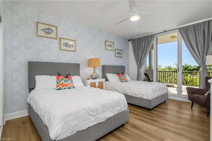 Guest Bedroom featuring en suite bath with wallpapered walls, wood finished floors, a ceiling fan, and access to private balcony
