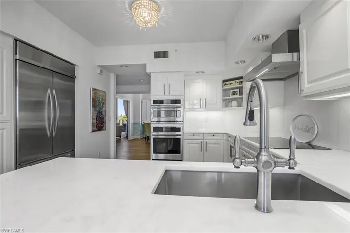 Kitchen featuring open shelves, appliances with stainless steel finishes, wall chimney exhaust hood, white cabinetry, and recessed lighting