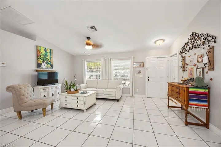 Living area with light tile patterned floors, a ceiling fan, and vaulted ceiling
