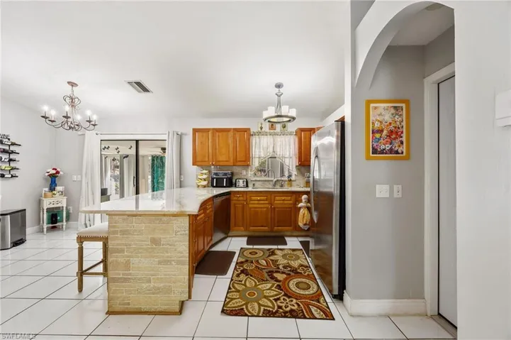 Kitchen with hanging lights, a peninsula, wood finish cabinets, a kitchen bar, and decorative backsplash