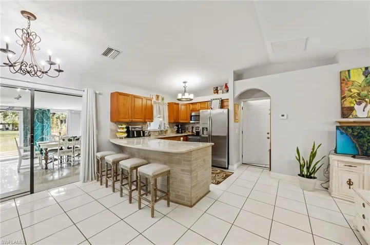 Kitchen with a chandelier, arched walkways, a kitchen bar, stainless steel appliances, and wood finish cabinetry